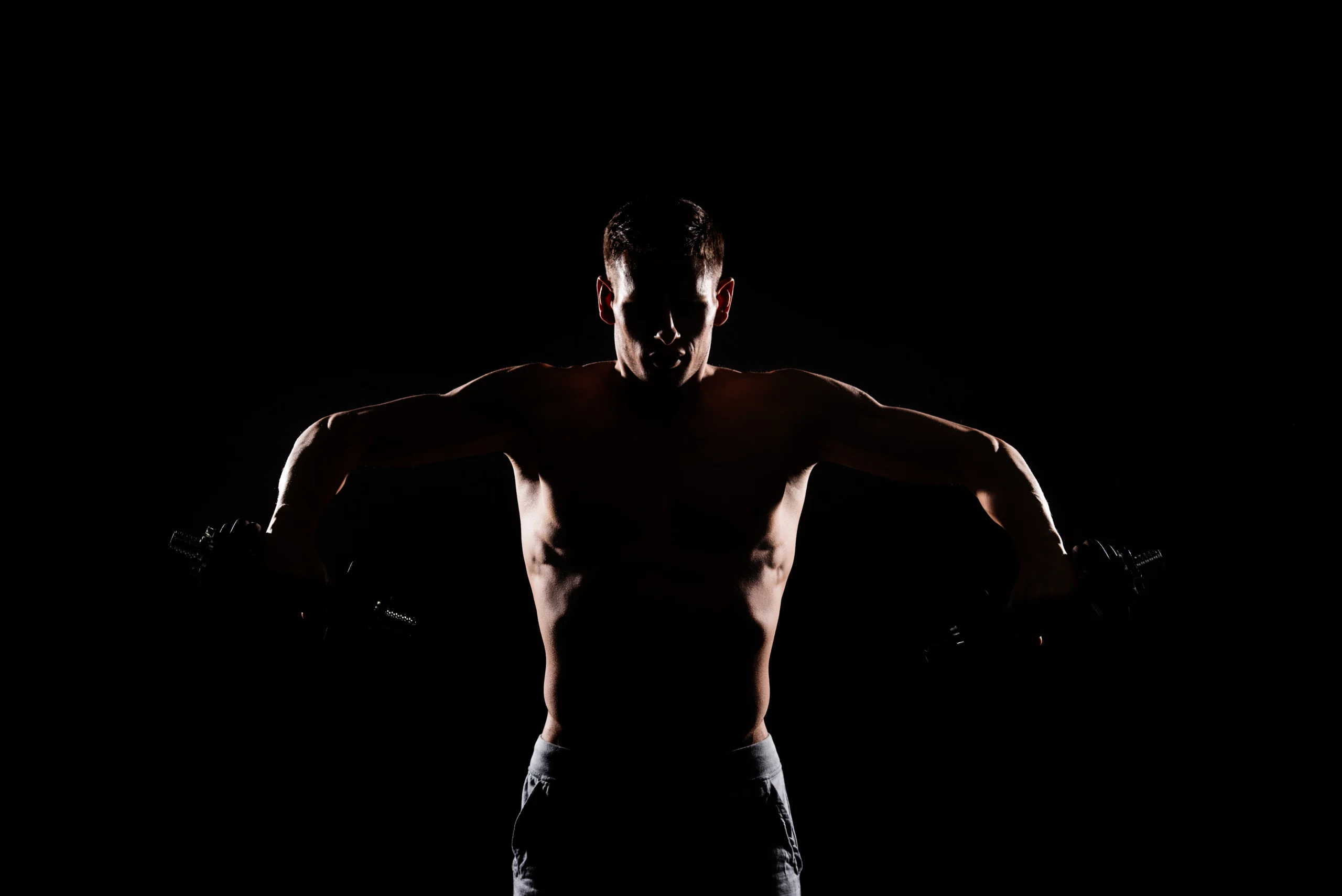 hombre musculoso levantando pesas sobre fondo oscuro